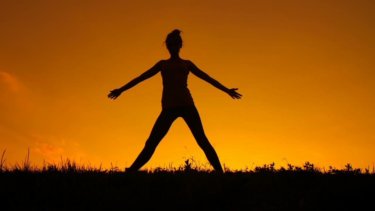 Silhouette of a woman doing yoga during a sunset - Free Stock Video