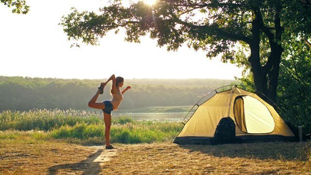 Woman stretching her body while camping in nature.