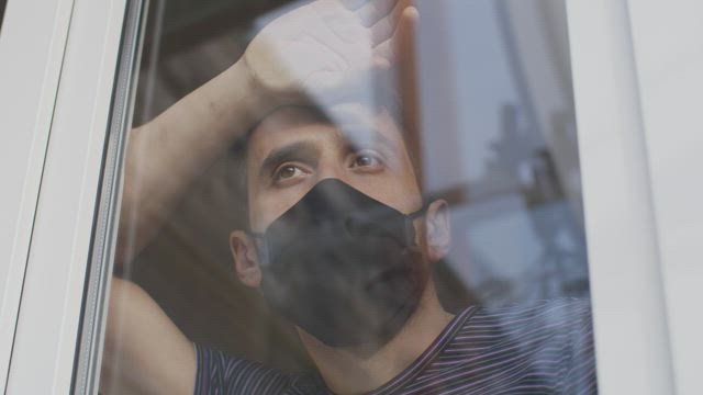 Man with mask looking out from the window.