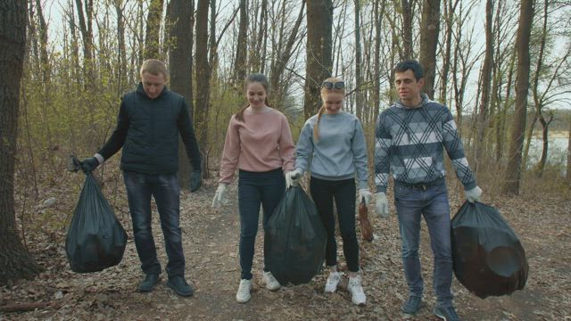 Volunteers with garbage bags in the forest.