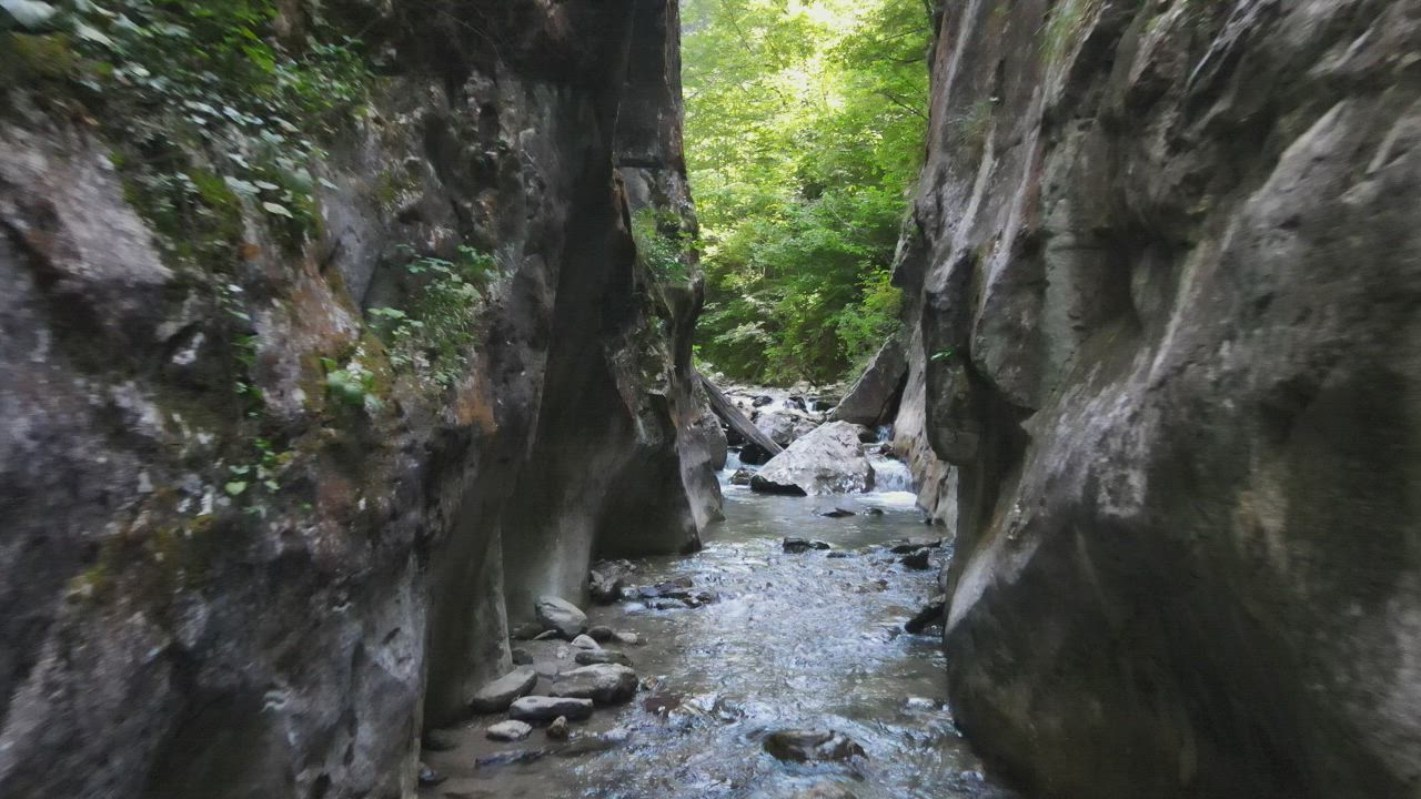 Man hiking in a stream between rocks - Free Stock Video