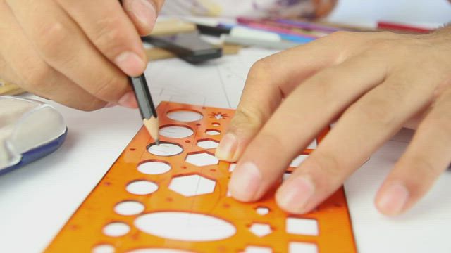 Hands of a person drawing circles with a template.