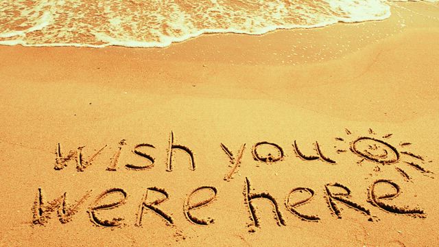 "I wish you were here" written in the sand.