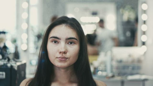 Pair of makeup artists working on a young woman.