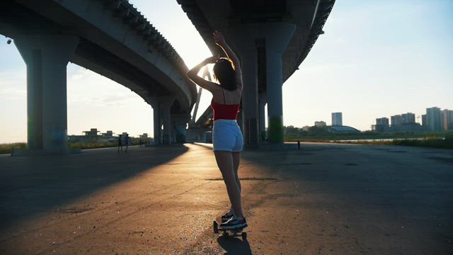 Girl skating in the afternoon under a bridge.