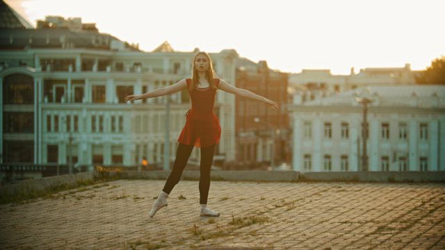 Girl dancing ballet on top of a building.