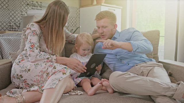 Happy family laughing while using a tablet.
