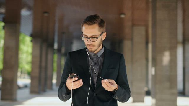 Businessman listen to music from his cellphone .
