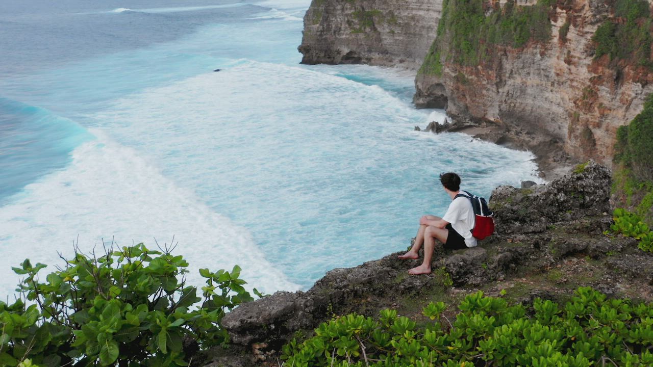 Man looking out to sea from a high cliff - Free Stock Video