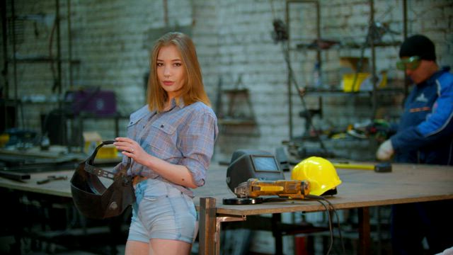 Woman putting on a welding mask in a blacksmith shop.