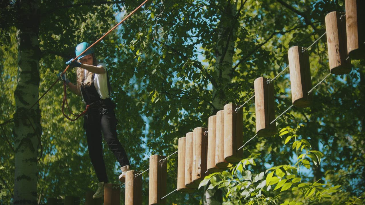 Girl crossing with a harness over a rope bridge - Free Stock Video