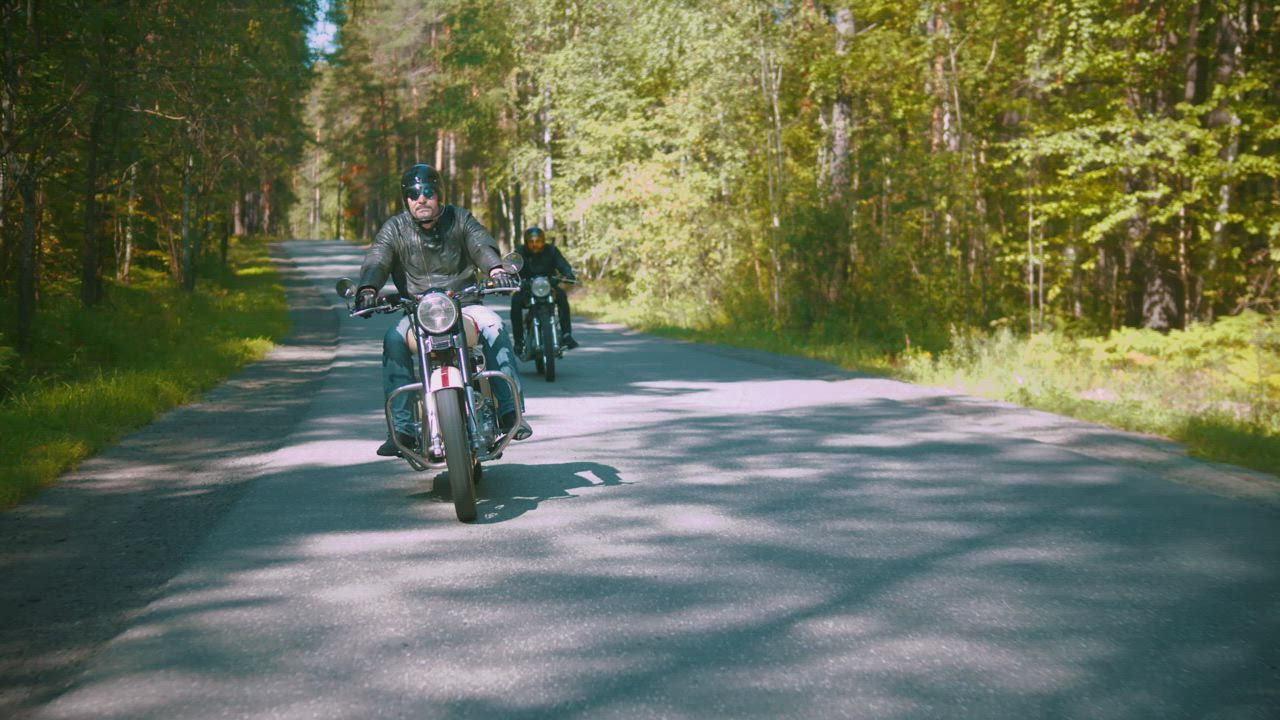 Two motorcyclists riding on a road in a forest - Free Stock Video