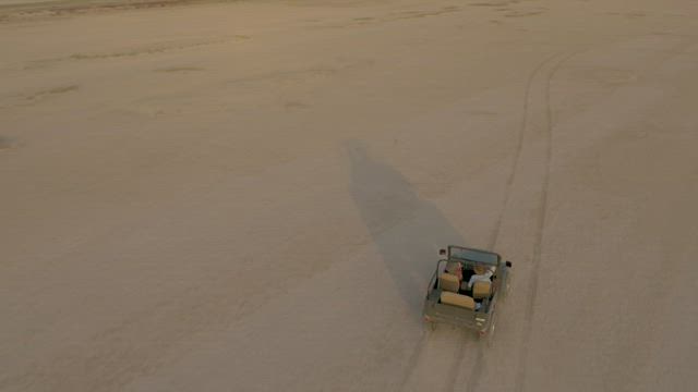 Jeep zigzagging through an immense desert.