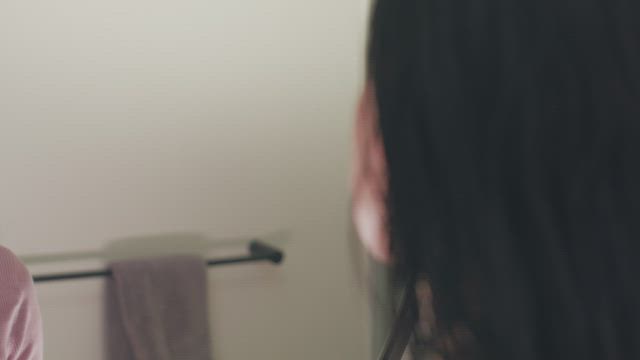 Woman putting on makeup in front of the mirror.