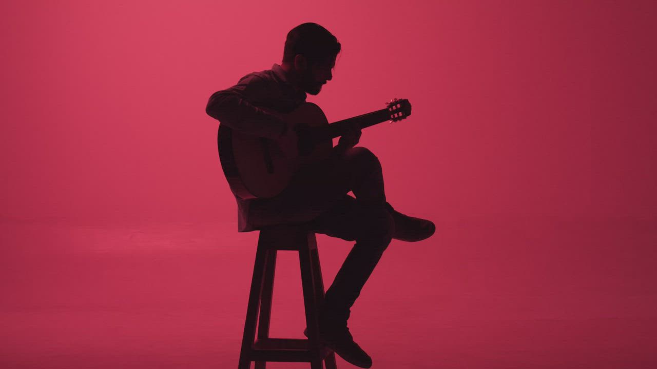 Guitarist playing in the dark on a pink background - Free Stock Video