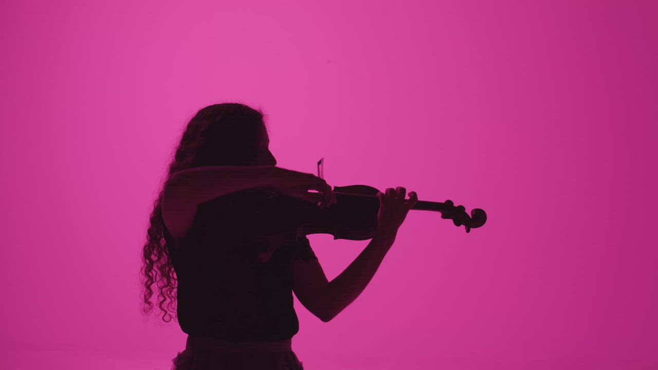 Fiddler in the dark playing on a pink background - Free Stock Video