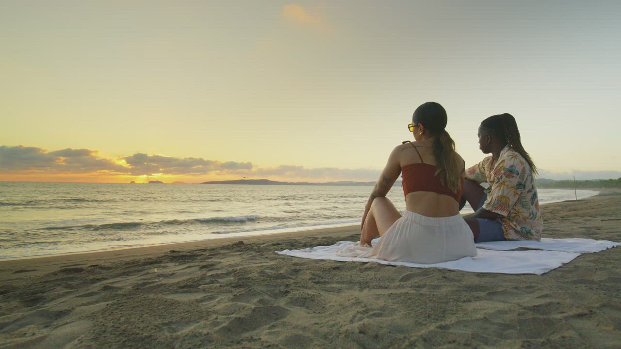 Woman and man watching the sunset from a beach - Free Stock Video