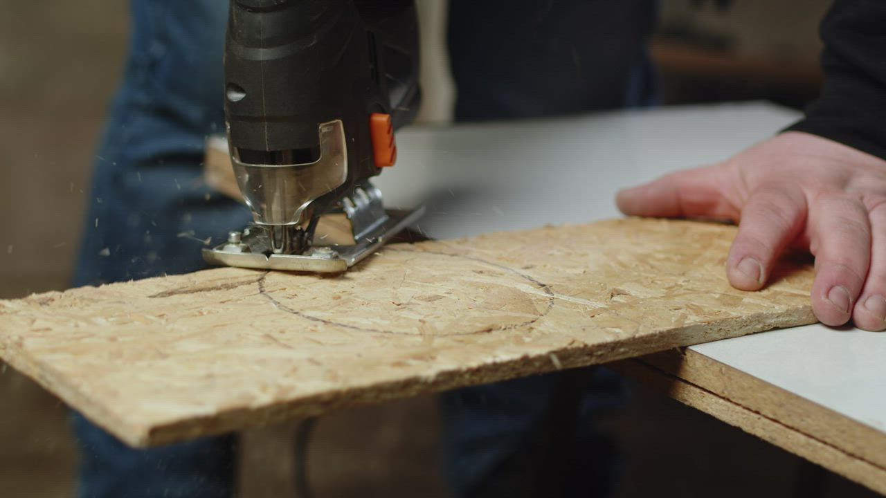 Carpenter uses a jigsaw to cut a perfect circle in a plank of wood ...