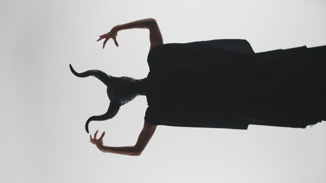 Silhouette of a scary horned witch against a white background.