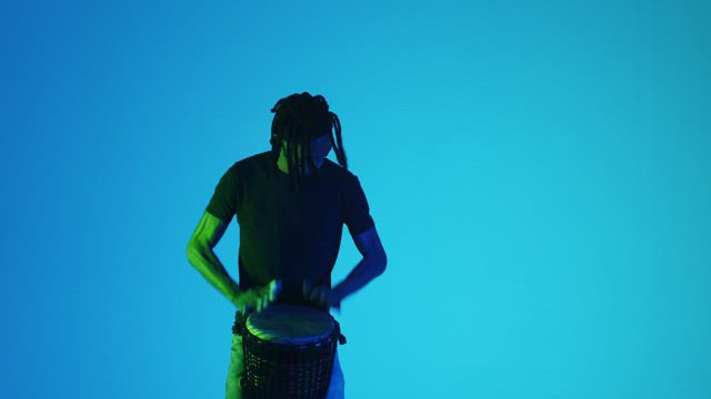 Man plays happily on the Bongo drums against a blue background.