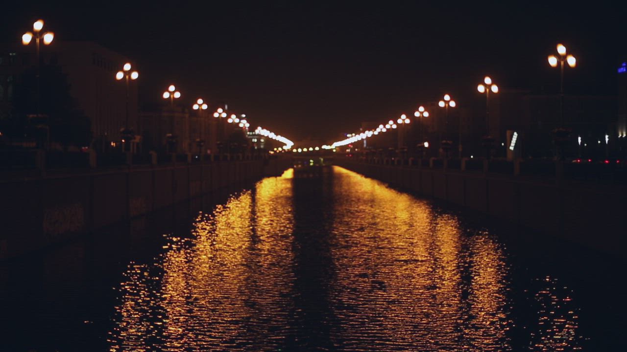 Lights reflect on water at night in a city - Free Stock Video