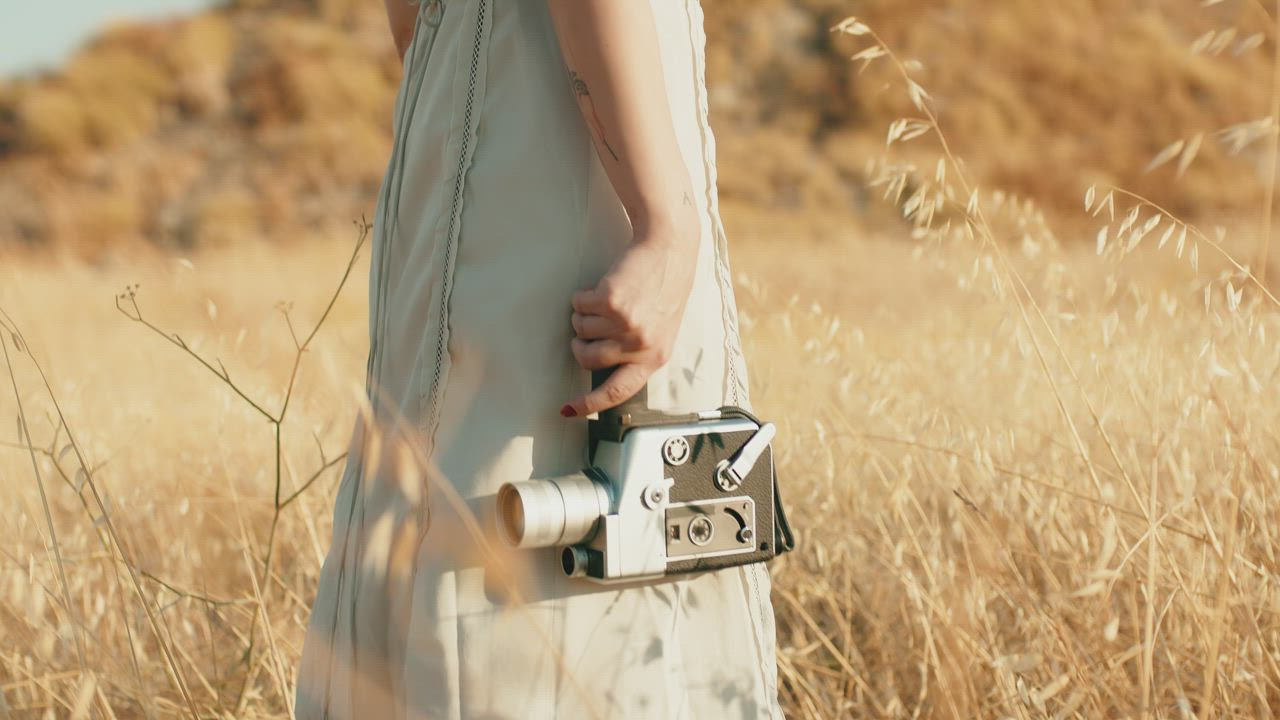 Standing in a field with a vintage camera about to film - Free Stock Video