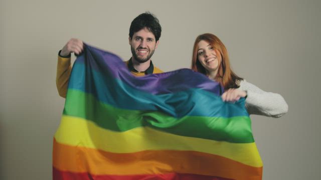 Happy couple waving a rainbow flag.