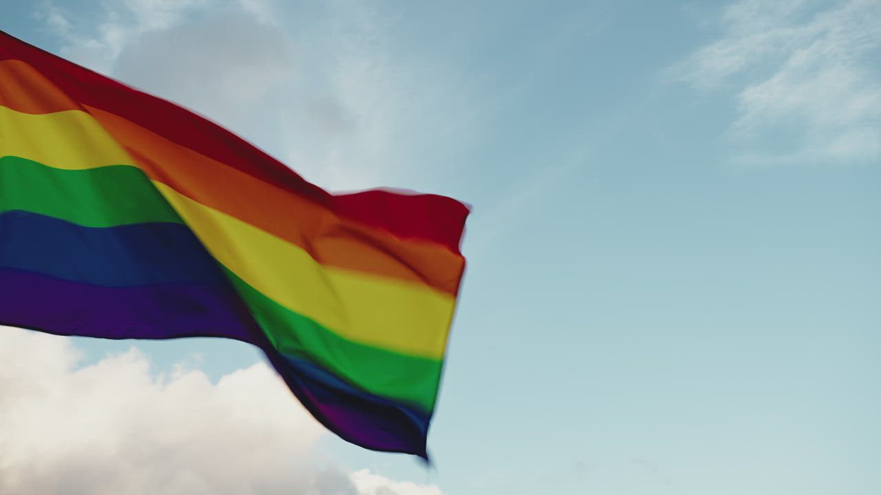 Rainbow flag waving in the blue sky - Free Stock Video