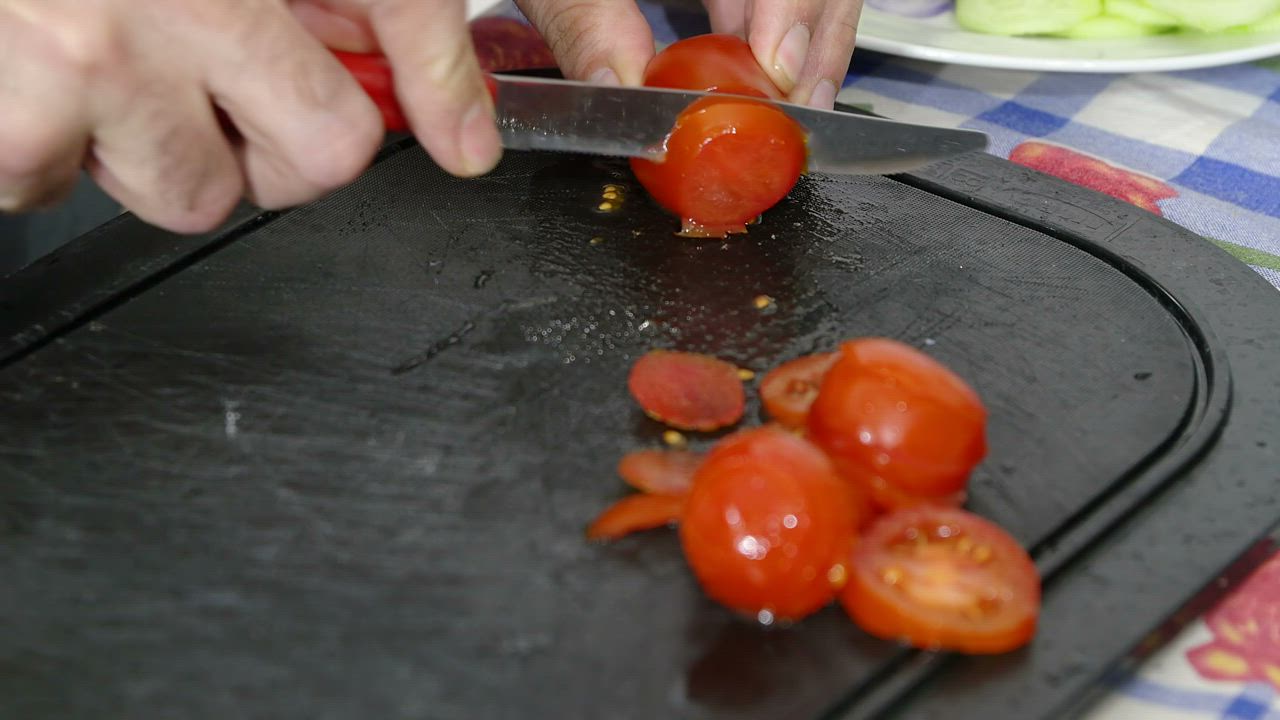Slicing tomatoes on a black chopping board - Free Stock Video