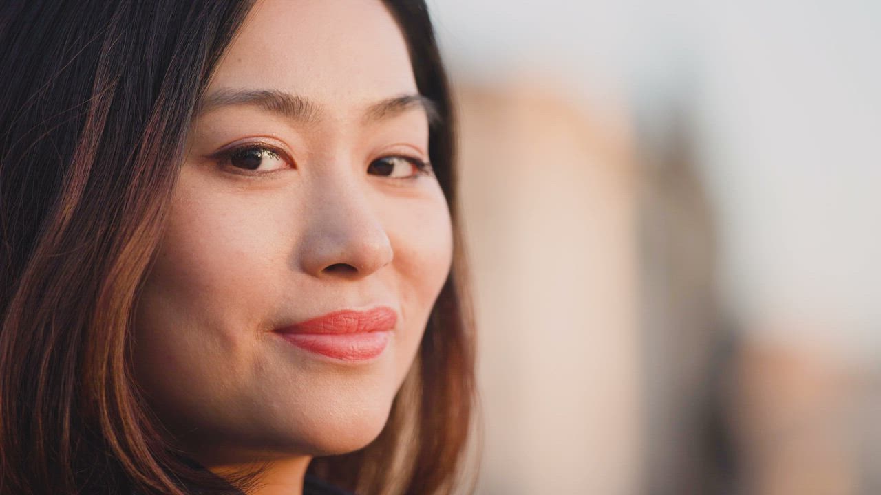 Close up of a woman smiling at the camera with a blurred background ...