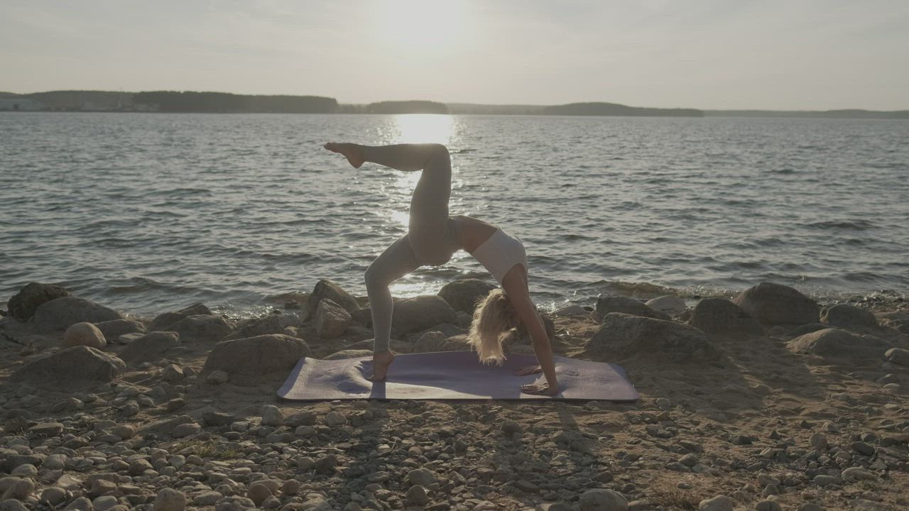 Young woman doing yoga at a sunset on a beach - Free Stock Video