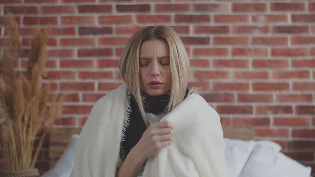 Woman wrapped in a blanket shivering while sick - Free Stock Video