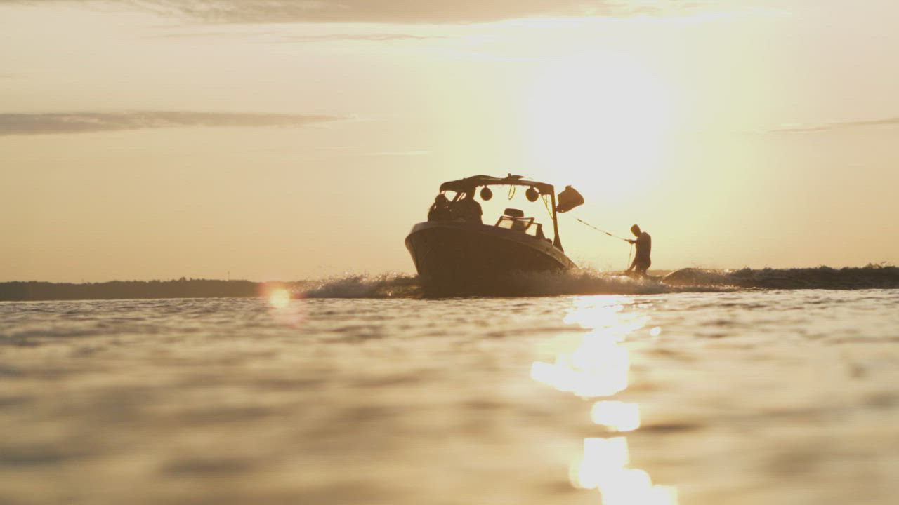 Wakeboarder riding behind boat at sunrise - Free Stock Video