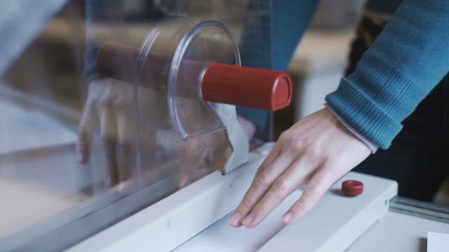 Close up of woman using paper cutting machine.