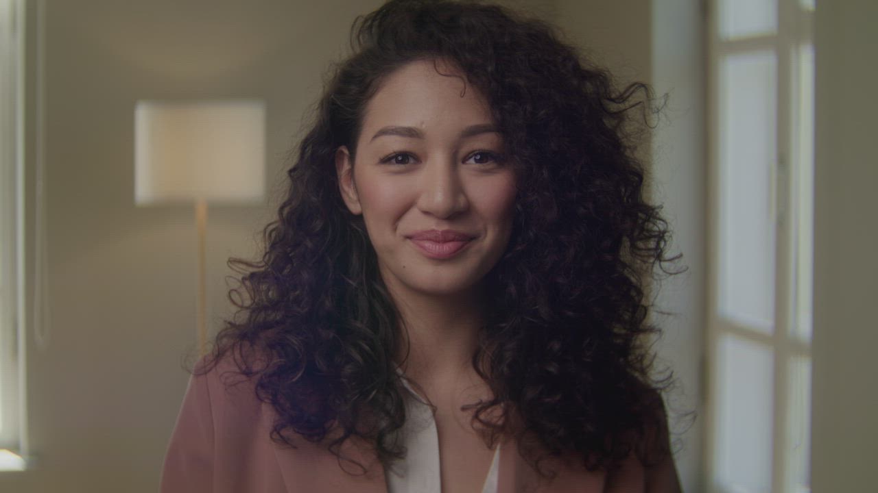 Young woman with curly hair smiling at the camera - Free Stock Video