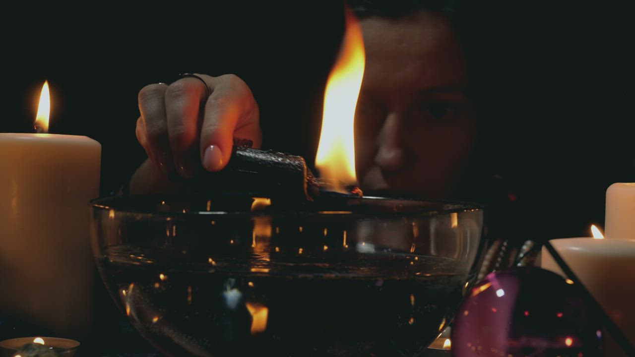 Woman moving a lit candle over a bowl in a spiritual ritual - Free ...