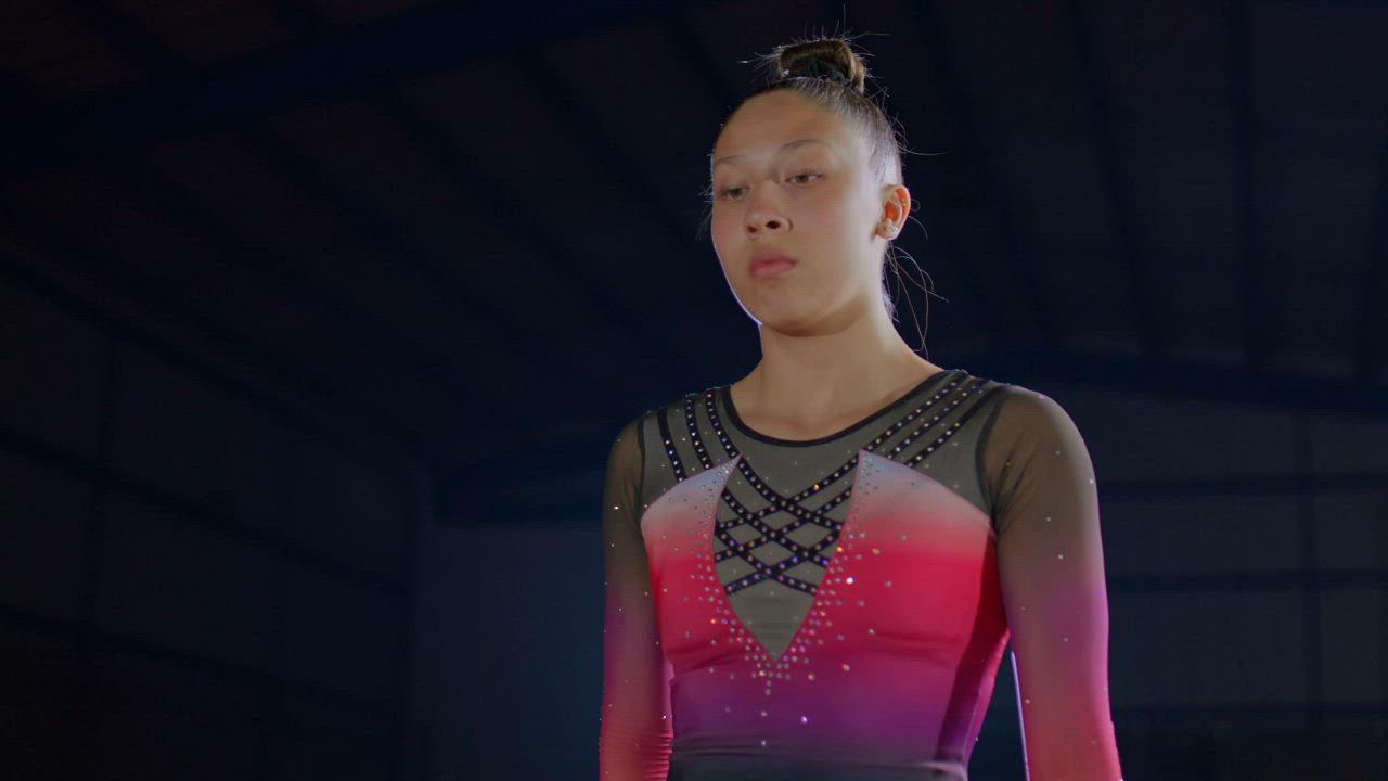 Gymnast in a leotard stretching on a balance beam - Free Stock Video