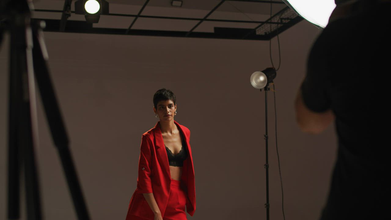 Model poses as camera lights flash in a studio - Free Stock Video