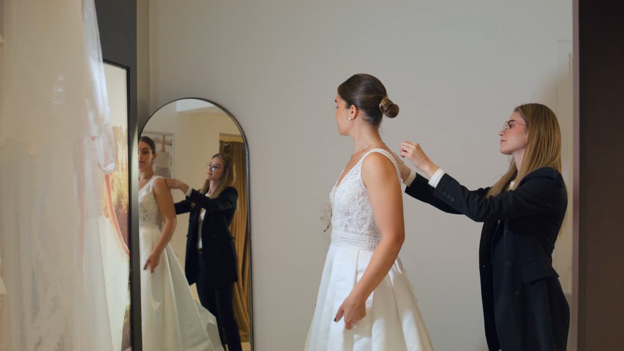 A young beautiful bride trying a wedding gown for the first time in ...