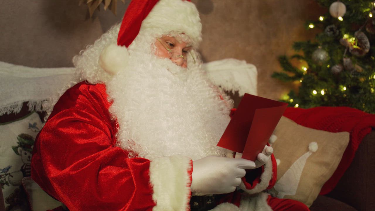 Santa Claus joyfully reads a letter on the couch - Free Stock Video