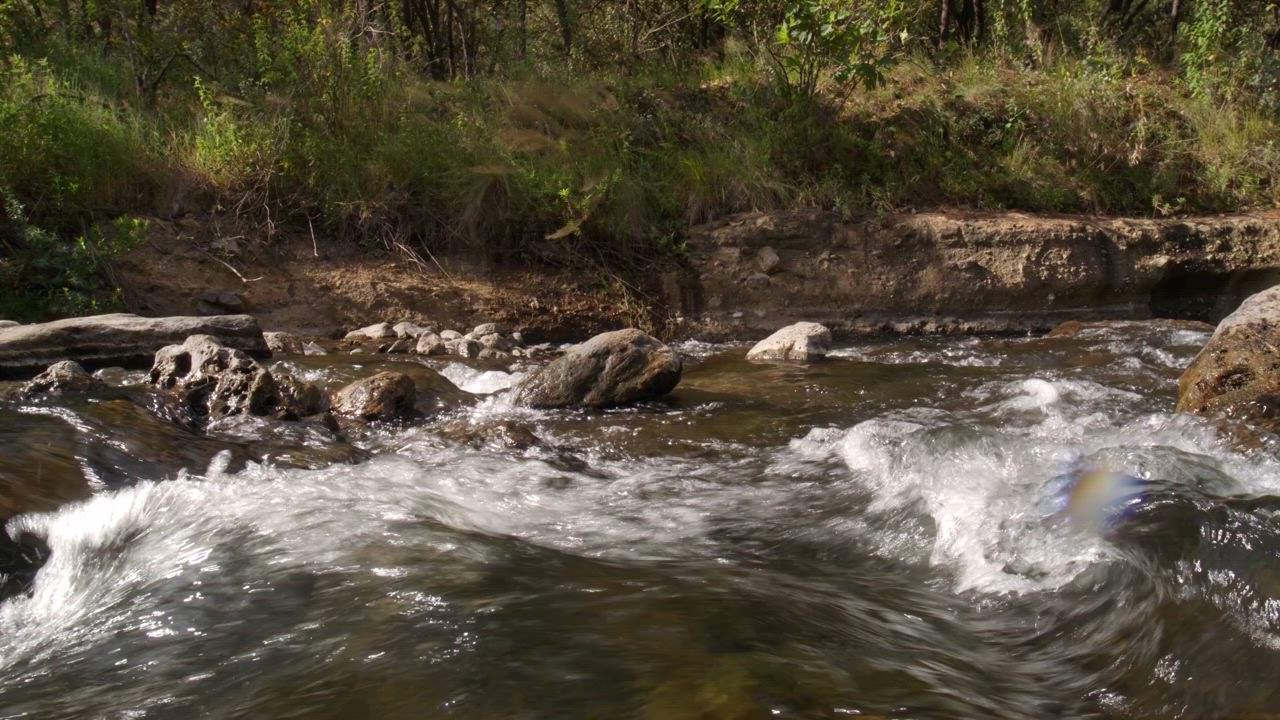 The water of the river creates splashes, foam and ripples when crashing ...