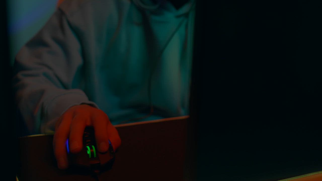 A young gamer moves the mouse with skill while playing in front of the ...