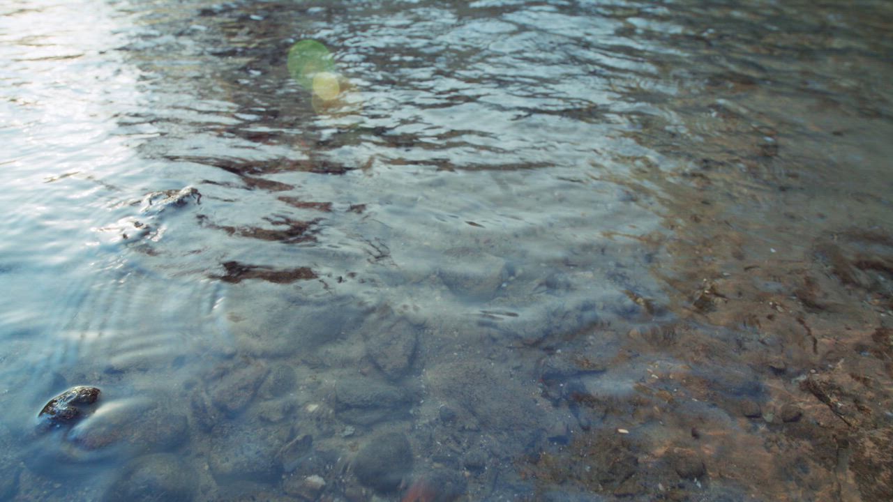 Water ripples move steadily over smooth stones - Free Stock Video