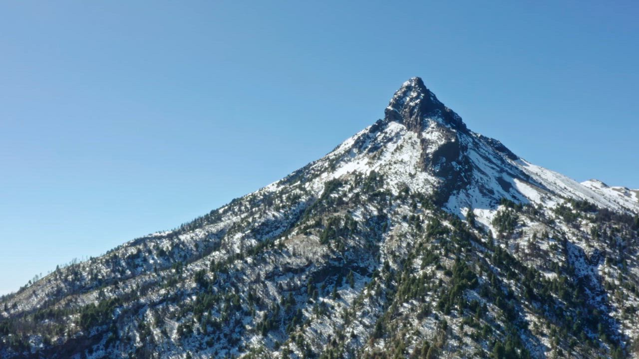 Aerial view of a snowy mountain on a sunny day - Free Stock Video