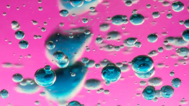 Texture of bubbles from a blue liquid on a pink background.