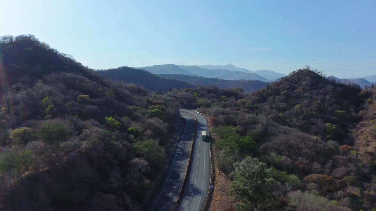 Aerial view of an asphalt road surrounded by the mountains covered in ...