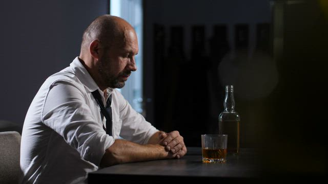 Man holding his head at a bar.