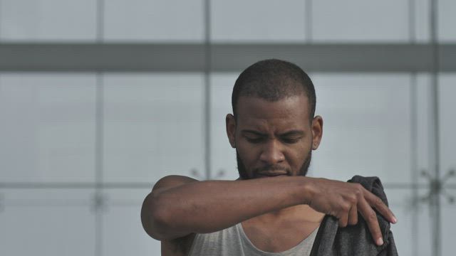Man puts on sleeveless hoodie.