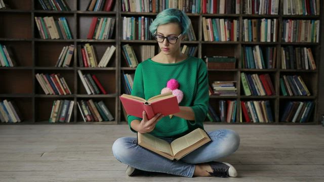 Woman with glasses reading in the library.