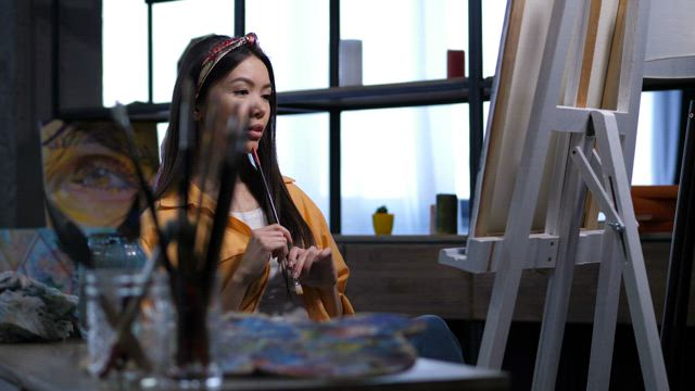 Female artist looking at her work.